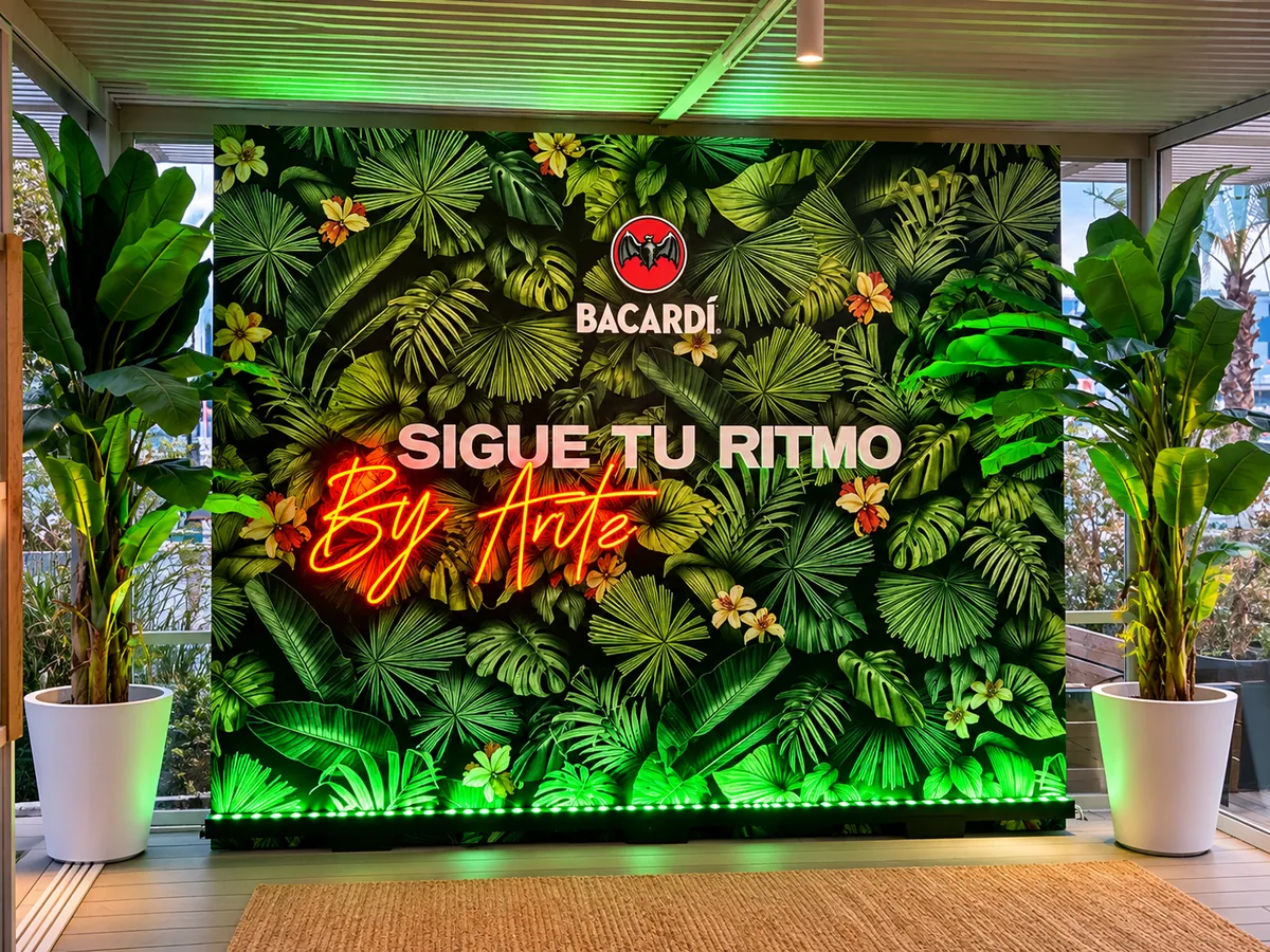 Muro vegetal con el rótulo de Bacardí y un neón rojo con el lema Sigue tu ritmo, entre plantas.